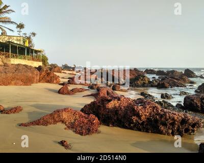 Red Volcanic Rocks on beach near Sweet Water Lake in Arambol, Goa, India Stock Photo