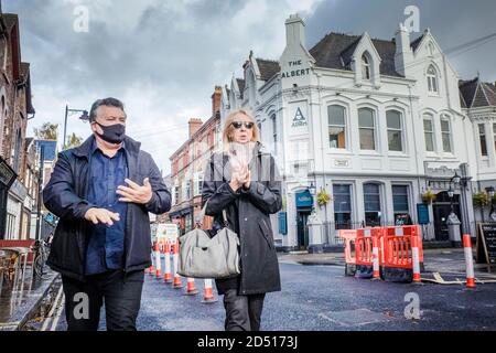 Liverpool Covid-19 Coronavirus lockdown. Masked man and unmasked woman wiping hands in Liverpool walk past a pub and bar. Stock Photo