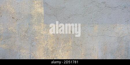 Yellow painted concrete wall background texture. Old grunge uneven surface with scratches and cracks. Rough plaster cement gypsum wall outdoors Stock Photo