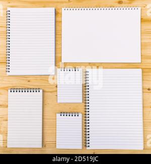 Empty notebooks on wooden background, template. Opened variety of spiral blank notepads, copybooks, different shapes. Copyspace. Stock Photo
