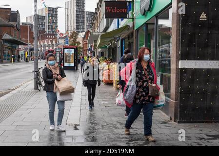 London, UK.  12 October 2020. Shoppers wearing a facemask pass by in Harrow town centre.  It is reported that five London boroughs had more than 100 new COVID-19 cases per 100,000 population in the week to October 8 — Richmond, Hackney, Ealing, Redbridge and Harrow.  As the UK experiences a rise in the number COVID-19 cases nationwide, Boris Johnson, Prime Minister is announcing in the House of Commons a new three-tier local lockdown system to tackle the spread of the virus.   Credit: Stephen Chung / Alamy Live News Stock Photo