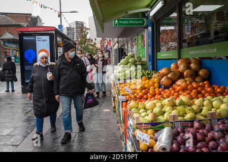 London, UK.  12 October 2020. Shoppers wearing facemasks walk by in Harrow town centre.  It is reported that five London boroughs had more than 100 new COVID-19 cases per 100,000 population in the week to October 8 — Richmond, Hackney, Ealing, Redbridge and Harrow.  As the UK experiences a rise in the number COVID-19 cases nationwide, Boris Johnson, Prime Minister is announcing in the House of Commons a new three-tier local lockdown system to tackle the spread of the virus.   Credit: Stephen Chung / Alamy Live News Stock Photo