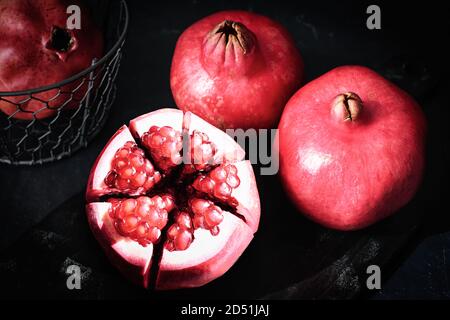 A peeled, juicy pomegranate on a dark wooden plate Stock Photo