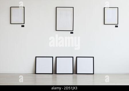Background image of empty black frames hanging on white wall at art gallery, copy space Stock Photo