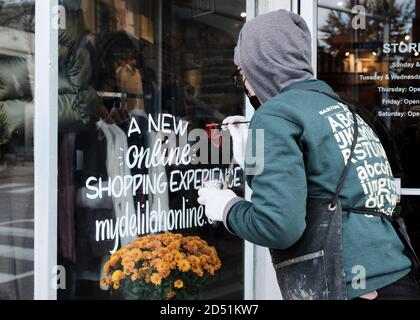 Pascale Arpin, Artist painting old-fashioned hand-lettered window lettering sign on store. the local artist has seen increase demand Stock Photo
