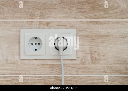 White electric power sockets on wall background with plugged electric plug. Stock Photo