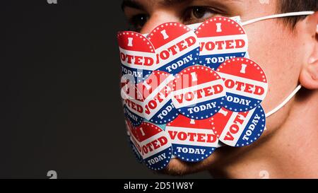 Man with face mask with many I voted today stickers. Coronavirus and American presidential elections concept. Stock Photo