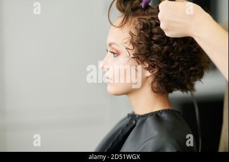 Making curly hair in professional salon side view Stock Photo