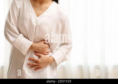 Young woman suffering from abdominal pain feeling stomachache, symptom of pms on white background Stock Photo
