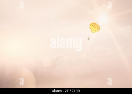 Paraglider in a pastel evening with the sun behind flying high in the sky Stock Photo