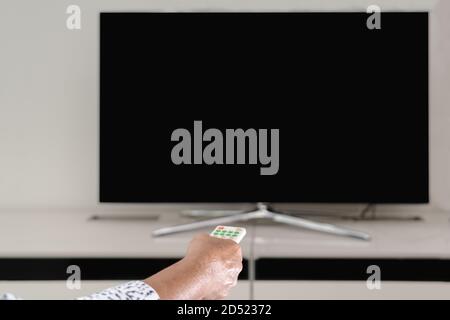senior women hand hold remote control of TV box watching, blank display Stock Photo