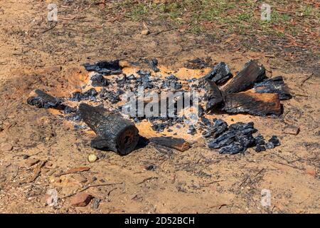 Burnt wood and coals from a recent campfire on brown dirt in The Blue Mountains in regional New South Wales in Australia Stock Photo