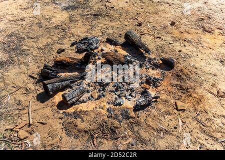 Burnt wood and coals from a recent campfire on brown dirt in The Blue Mountains in regional New South Wales in Australia Stock Photo