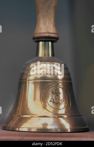 Old ship hand bell made of yellow metal with an anchor pattern, close-up Stock Photo
