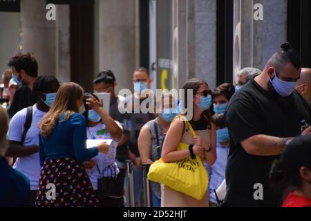 Customers with protective face masks queuing outside a shop in Central London, UK. Stock Photo