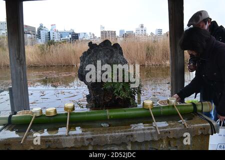 Tokyo, Japan-2/23/16: A Couple interacts with the purification fountain located at the Shinobazu-no-ike Bentendo shrine. Stock Photo