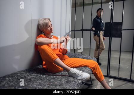 Girl convicted drug dealer in an orange jumpsuit in his cell on a prison bunk. Stock Photo