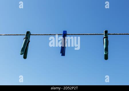 clothespins hanging on a rope. Three clothespins hang from a clothesline. Against the background of the blue sky. Stock Photo
