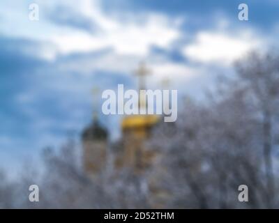 Defocused photography. Winter city in the snow. The Church with Golden crosses is surrounded by snow-covered trees. Blurred background for your design Stock Photo