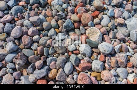 small smooth stones, stony seashore, sea pebbles on the sand Stock Photo