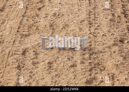 the word dust standing on dusty road surface in linear perspective Stock Photo