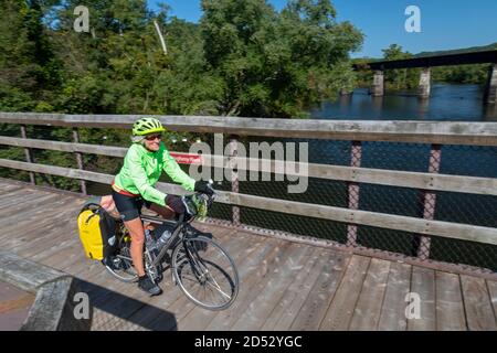 Confluence, Pennsylvania - A senior citizen bicycle rider headed for Washington, D.C. on the Great Allegheny Passage trail crosses the Youghiogheny Ri Stock Photo