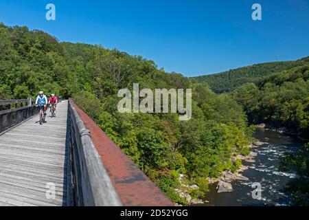 Ohiopyle, Pennsylvania - Bicycle riders cross a bridge over the Youghiogheny River on the Great Allegheny Passage trail in Ohiopyle State Park. The tr Stock Photo