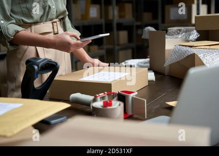 Female small business owner using mobile app on smartphone checking parcel box. Stock Photo