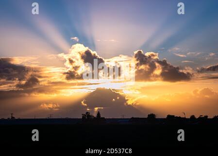Sunbeams coming from behind colorful clouds Stock Photo