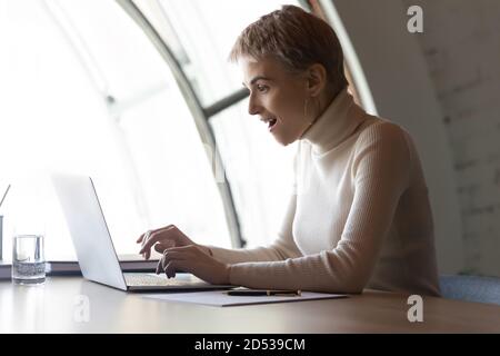 Excited female employee surprised by news on laptop Stock Photo