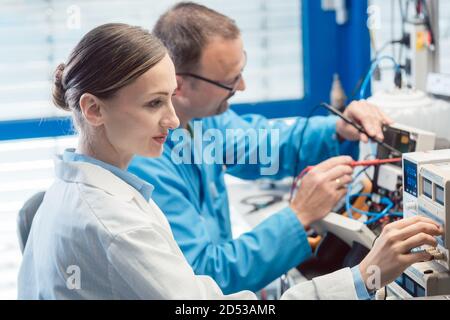Two electronic engineers on the test bench measuring a new product Stock Photo
