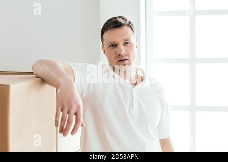 pensive young man standing near cardboard boxes Stock Photo