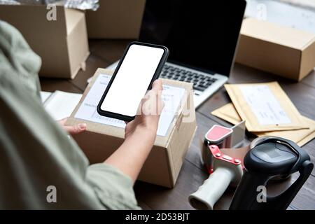 Female warehouse worker holding parcel box using mobile application. Stock Photo