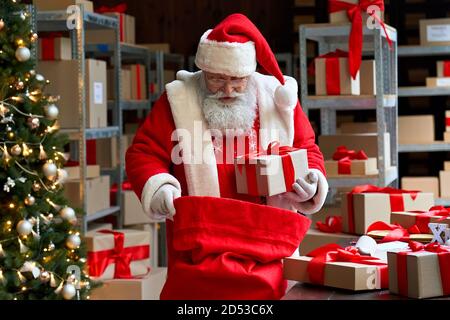 Santa Claus packing present gift boxes in sack bag preparing fast xmas delivery. Stock Photo