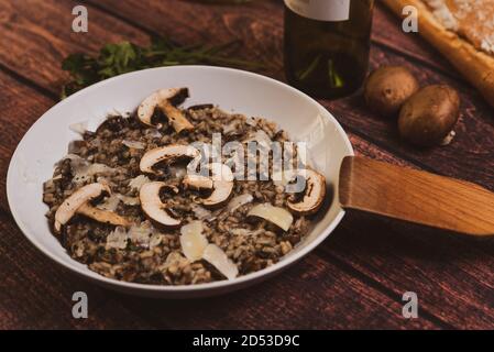 portobello mushrooms risotto, italian food known as 'risotto ai funghi', top view with warm light, parsley, side view, on dark brown wooden table. par Stock Photo