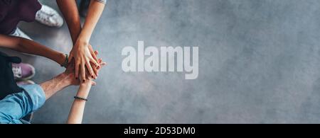 People's hands on top of each other. Top view of young group with hands on stack symbolizing teamwork. Stock Photo