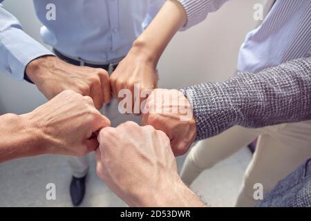 Celebreting success. Top view of different ethnicity business people doing fists bump while standing in the office Stock Photo