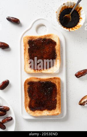 Fresh toasts with dates jam without sugar on white table. View from above. Vertical. Stock Photo