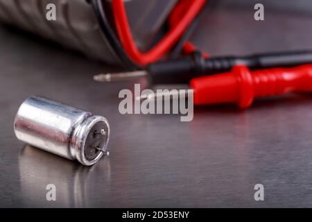 Capacitor and electrical meter. Measurement work in an electrical workshop. Metallic background. Stock Photo