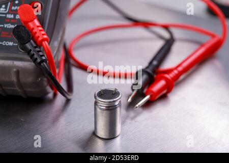 Capacitor and electrical meter. Measurement work in an electrical workshop. Metallic background. Stock Photo