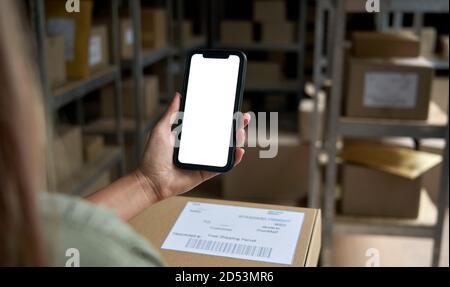 Female warehouse worker holding parcel box using mobile application. Stock Photo