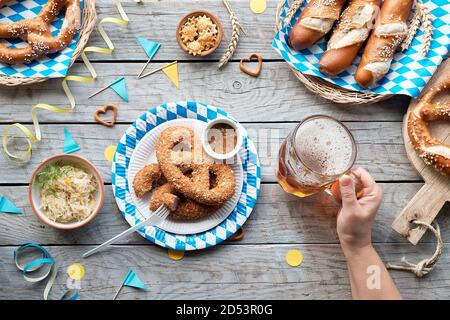 Celebrating Oktoberfest alone. Traditional food and beer, top view on wooden table, Stock Photo