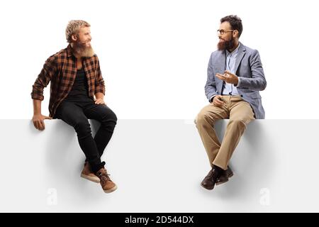 Two bearded men sitting on a blank panel and having a conversation isolated on white background Stock Photo