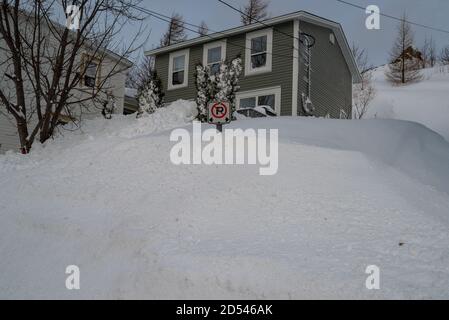 St. John's, Newfoundland/Canada - October 2020: A green wooden historic house with white trim. There's snow piled up in front of the house.