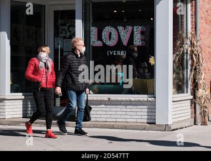 Couple walking holding hands by store window with the word "Love" printed. They are not looking at each other Stock Photo