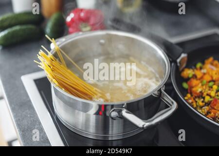 Boiling pot with cooking spaghetti pasta in the kitchen. Closeup Stock Photo