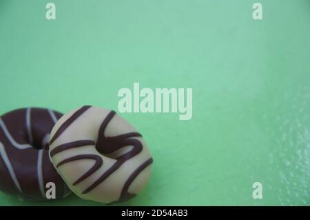 Image with copy space of a pair of black and white chocolate donuts on light green background Stock Photo