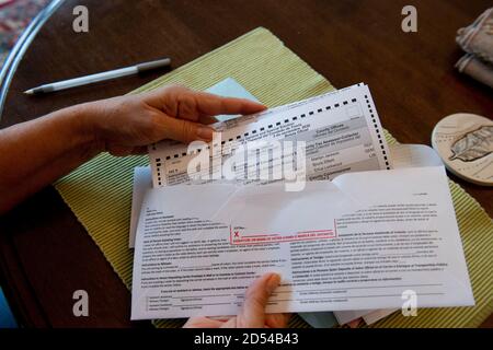 Austin, Texas, October 12, 2020: Woman encloses her completed mail-in absentee ballot into the provided official envelope. The form must to be either mailed back or dropped off in person in time to be counted before the November 3rd election day. Stock Photo