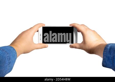 Isolated first person view photo of a male hands in jeans shirt holding a smartphone horizontally on white background. Stock Photo