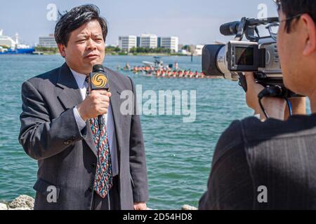 Miami Florida,Bayfront Park Hong Kong Dragon Boat Race Festival,Asian man male media reporter reporting television tv broadcast,microphone cameraman s Stock Photo